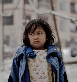 Girl looking away while standing during snowfall