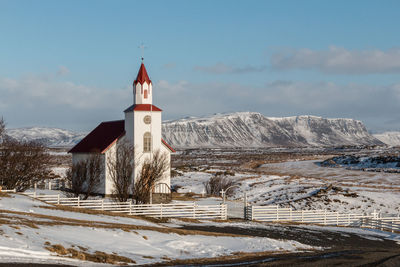 Church on snow covered landscape against sky during winter