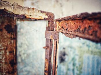 Close-up of rusty metal on wood against wall