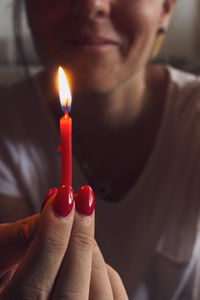 Close-up of person holding birthday burning candle 