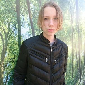 Portrait of teenage girl standing by tree in forest