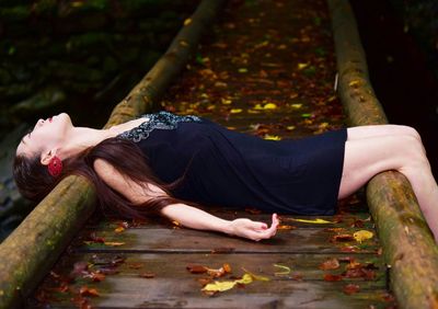 Midsection of woman sitting on wood during autumn