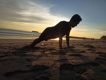 Horse on beach against sky during sunset