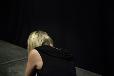 Rear view of woman standing against black background