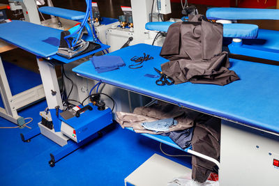 Professional work tables with blue upholstery fabric of a dress cutter in an atelier studio.