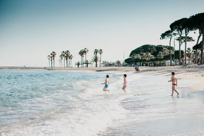 People playing on beach against clear sky