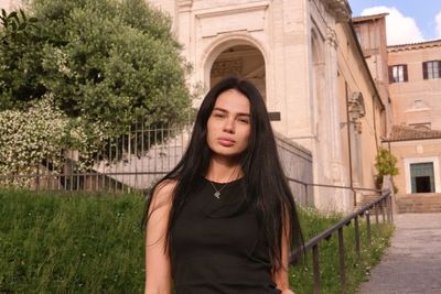 Portrait of young woman standing against trees