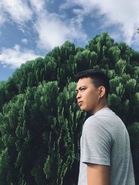 Young woman looking away against trees