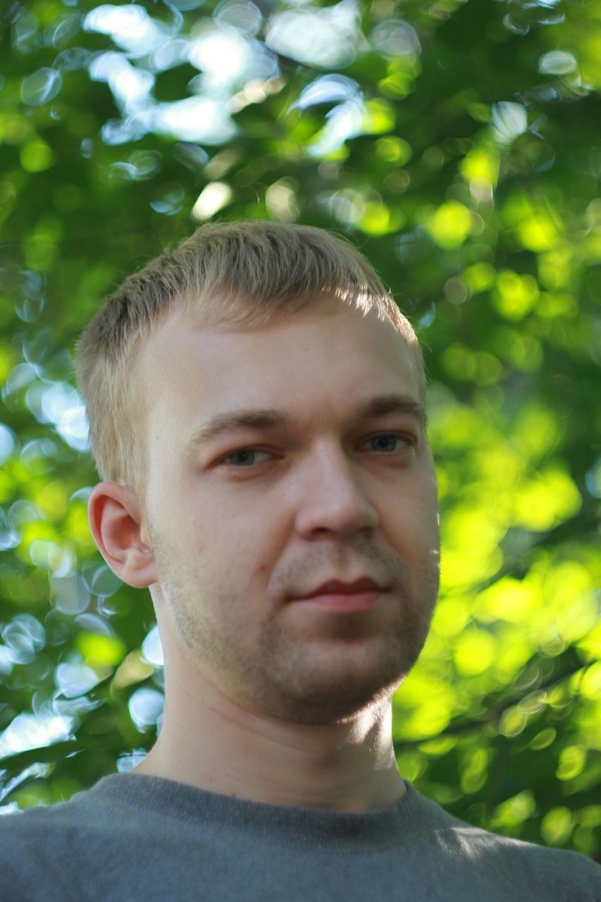 portrait, headshot, looking at camera, close-up, person, lifestyles, front view, focus on foreground, human face, young adult, head and shoulders, leisure activity, young men, tree, contemplation, serious, day