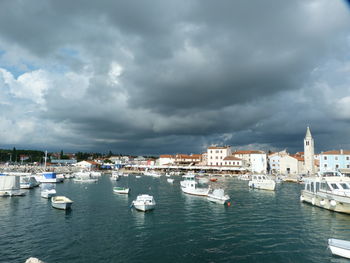 Boats in harbor against cloudy sky