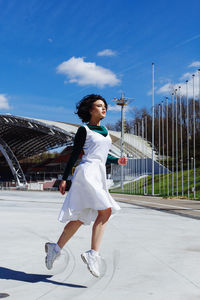 Fashionable woman jumping outdoors during sunny day