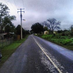 Empty road along bare trees