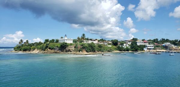 Buildings by sea against sky