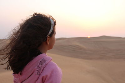 Girl looking to the sunset on dubai's desert