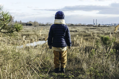 Rear view of man standing on field against sky