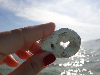 Close-up of hand holding umbrella against sky