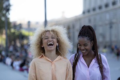 Portrait of happy women friends laughing while walking in madrid city