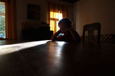 Portrait of boy sitting on table at home