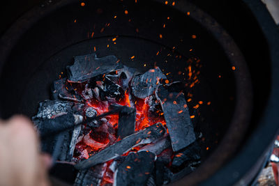 High angle view of bonfire, glowing charcoal and sparks.