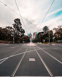 Road by trees against sky in city