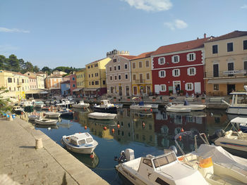 Boats moored at harbor against buildings in city