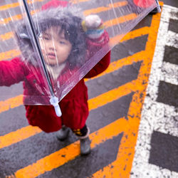 High angle view of girl holding umbrella standing outdoors