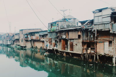 Buildings by river against sky