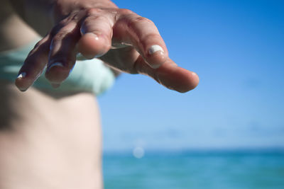 Midsection of woman at beach against sea