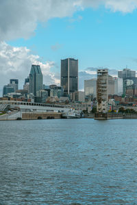 Sea by buildings against sky in city