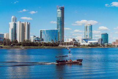 Sailboats in city by buildings against sky