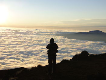 Silhouette woman standing on mountain against sky during sunset