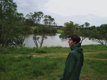 Side view of man standing by lake against sky