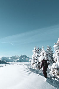 Rear view of person standing on snowcapped mountain against sky