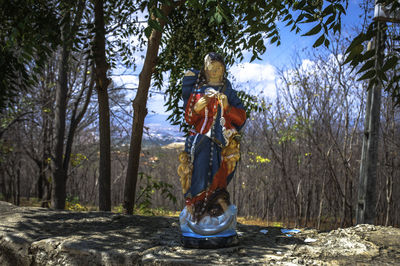 Old statue on footpath in forest