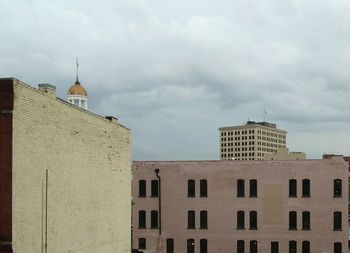 View of buildings in city against cloudy sky
