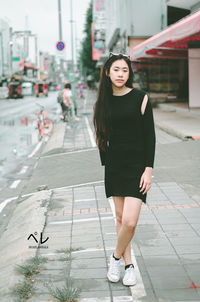 Portrait of woman standing on footpath in city