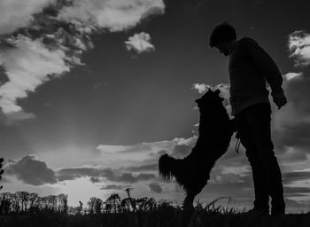 Low angle view of man standing against cloudy sky