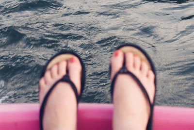 Low section of woman on pink railing against lake