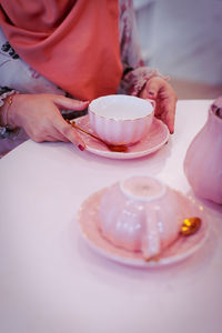 Midsection of woman holding tea cup on table