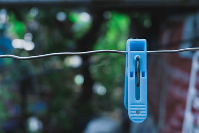 Close-up of clothespins hanging on rope against blurred background