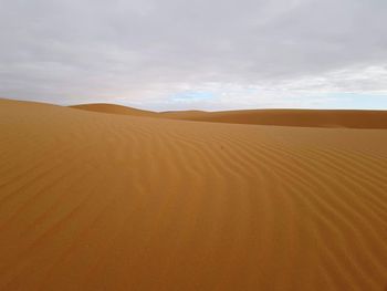 Sand dunes in desert against sky