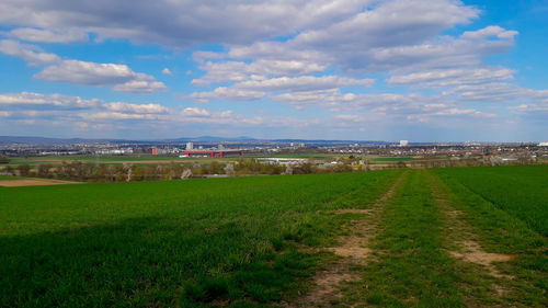 Scenic view of field against sky in city