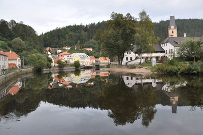 Houses by lake and buildings against sky