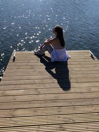 High angle view of woman sitting on pier over sea