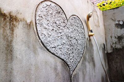 Low angle view of heart shape on wall by shower handle in bathroom