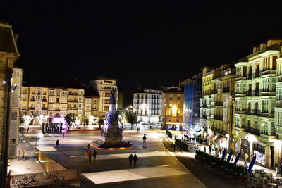 Vehicles on road against buildings in city at night