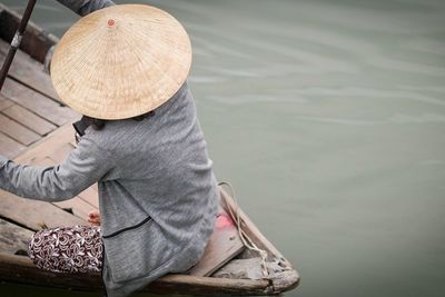 High angle view of woman wearing hat sitting in nautical vessel on lake