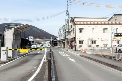 Road by buildings in city against sky