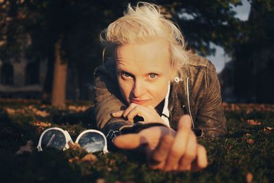 Portrait of woman lying on grass against trees