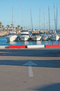 Sailboats moored on harbor against clear sky